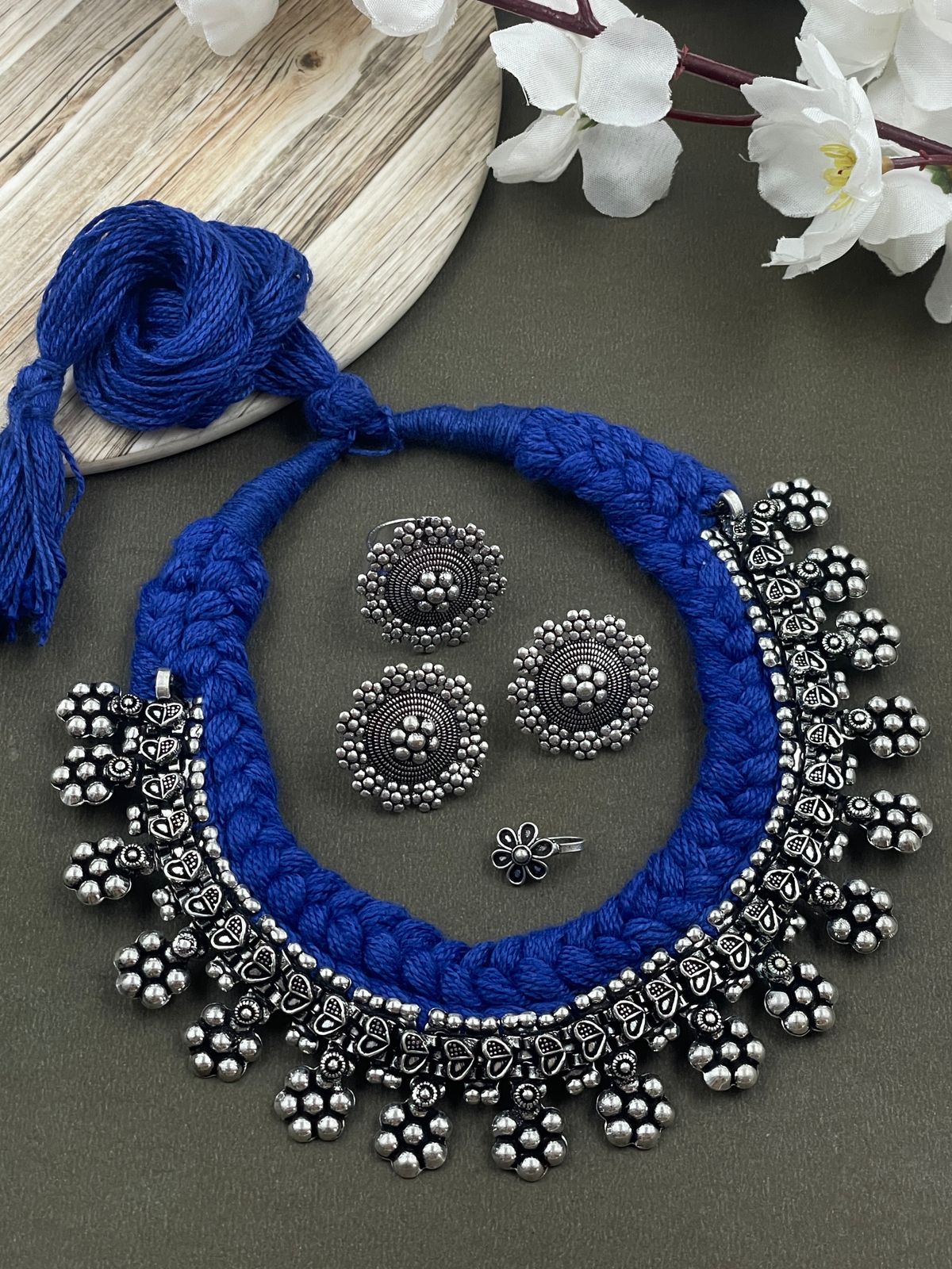 Threaded choker set in blue with an oxidized brass necklace featuring heart and flower designs, complemented by matching flower ring, studs, and nosepin
