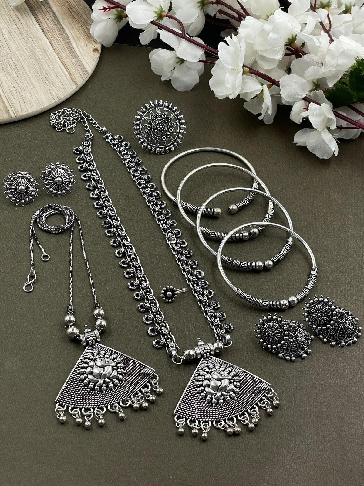 Oxidized jewelry set featuring two pendants of Ganpati design, a ring, earrings, kada, nosepin, and toe ring, all crafted in brass with intricate detailing.