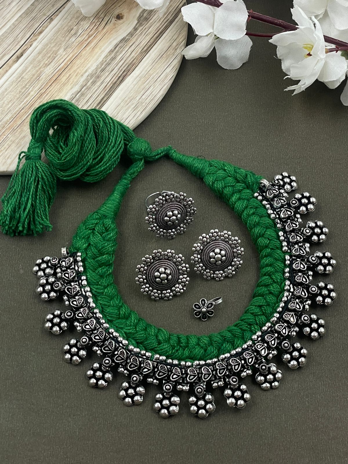 Threaded choker set in green with an oxidised brass necklace featuring heart and flower designs, complemented by matching flower ring, studs, and nosepin