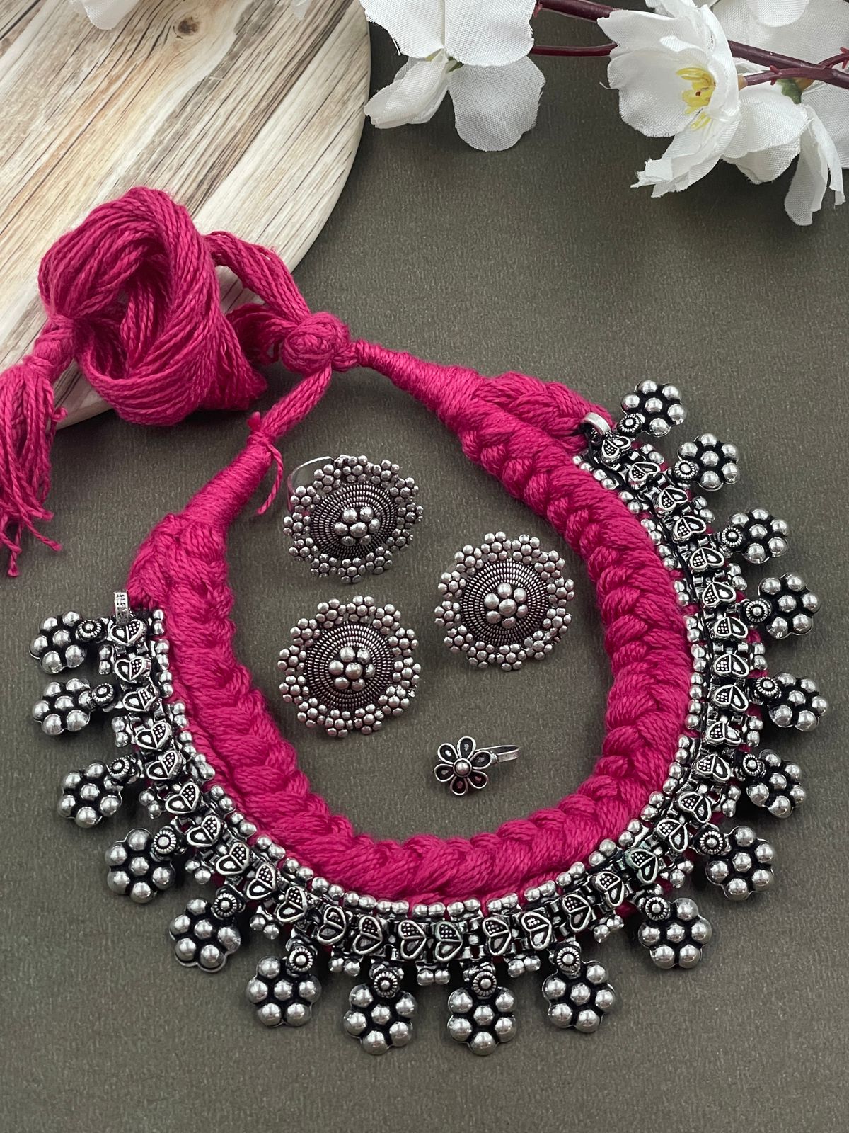 Threaded choker set in pink with an oxidised brass necklace featuring heart and flower designs, complemented by matching flower ring, studs, and nosepin