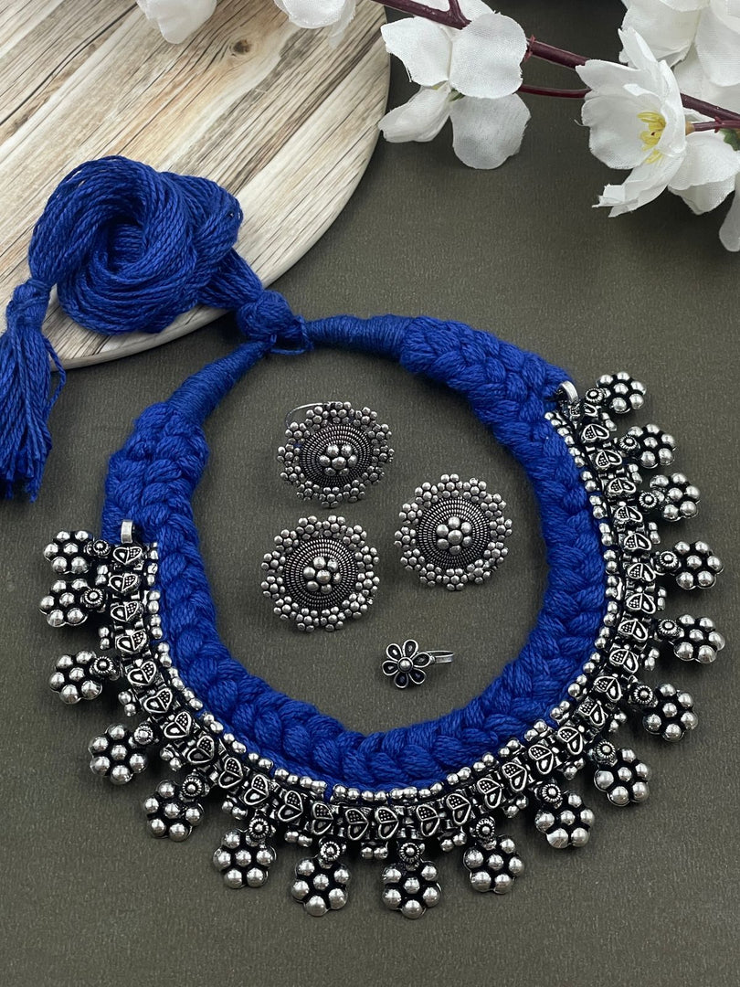 Threaded choker set in blue with an oxidized brass necklace featuring heart and flower designs, complemented by matching flower  ring, studs, and nosepin