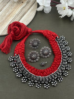 Load image into Gallery viewer, Threaded choker set in red with an oxidized brass necklace featuring heart and flower designs, complemented by matching flower  ring, studs, and nosepin